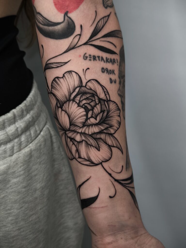 Tatuaje de peonía con lettering en antebrazo