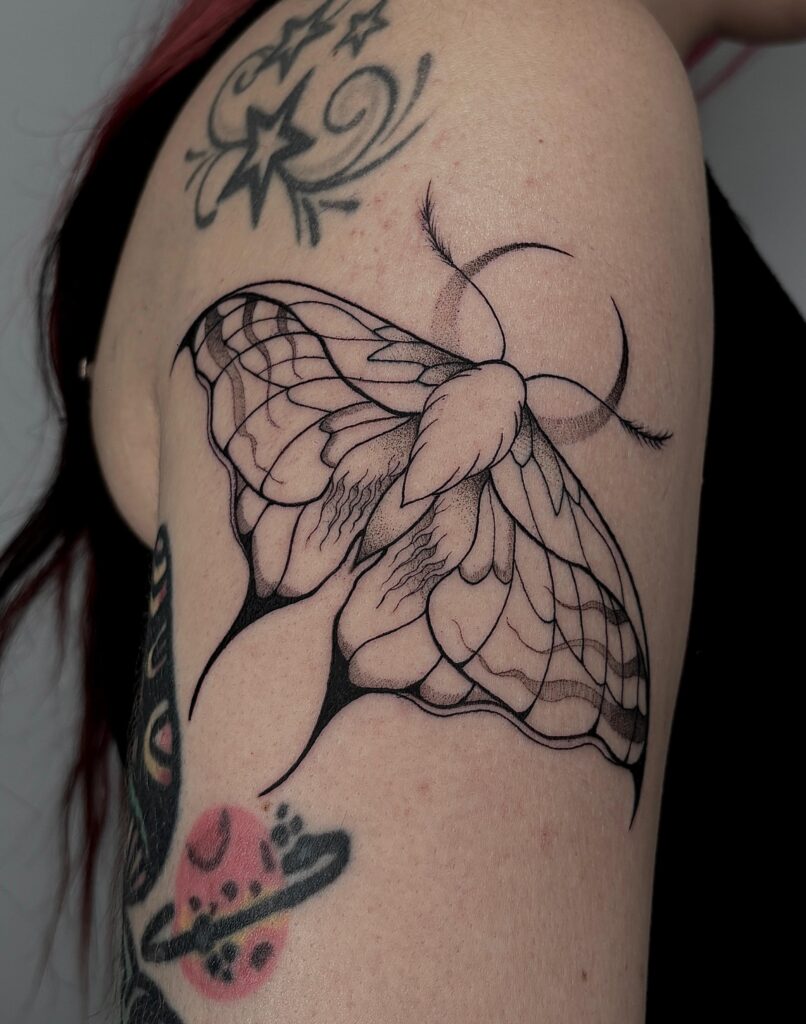 Tatuaje de polilla en línea con detalles de color en el brazo en Bilbao