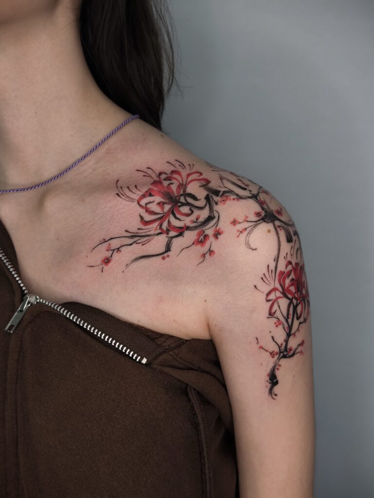 Tatuaje floral de rama de cerezo en rojo sobre el hombro en Bilbao